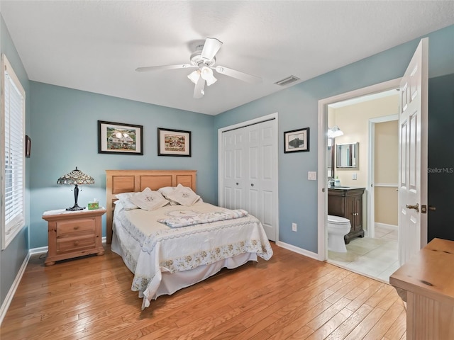 bedroom with ensuite bathroom, light hardwood / wood-style flooring, ceiling fan, and a closet