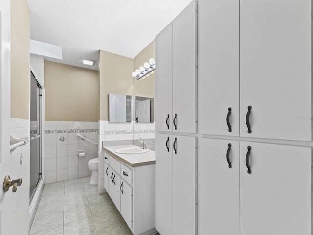 bathroom with vanity, toilet, tile patterned flooring, and tile walls