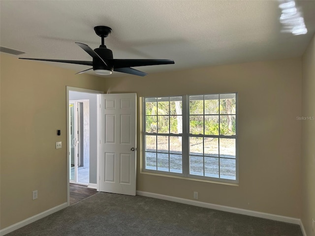 spare room with ceiling fan and dark carpet