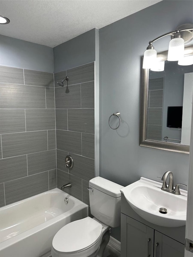 full bathroom featuring vanity, tiled shower / bath, toilet, and a textured ceiling