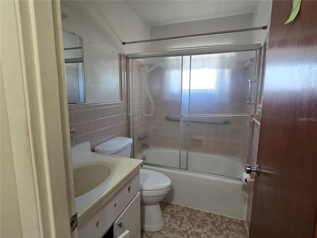 full bathroom featuring enclosed tub / shower combo, vanity, toilet, and tile walls