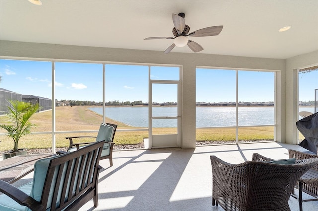 sunroom featuring ceiling fan and a water view