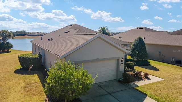 view of side of home featuring a garage, a yard, and a water view