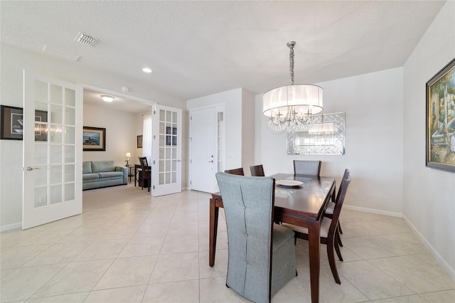 tiled dining space with a textured ceiling, a chandelier, and french doors