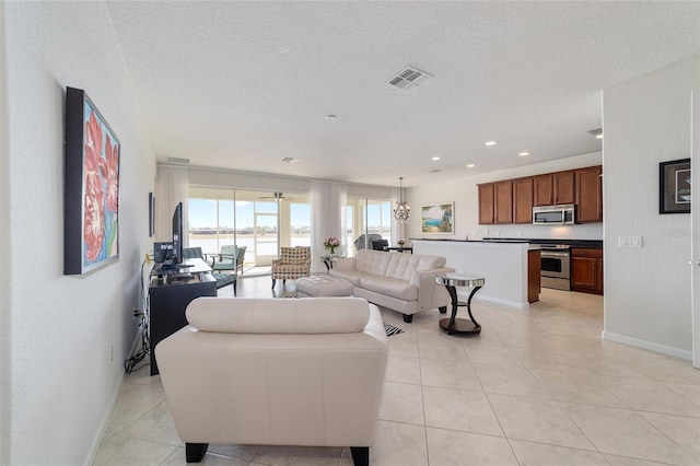 living room with light tile patterned floors, a notable chandelier, and a textured ceiling