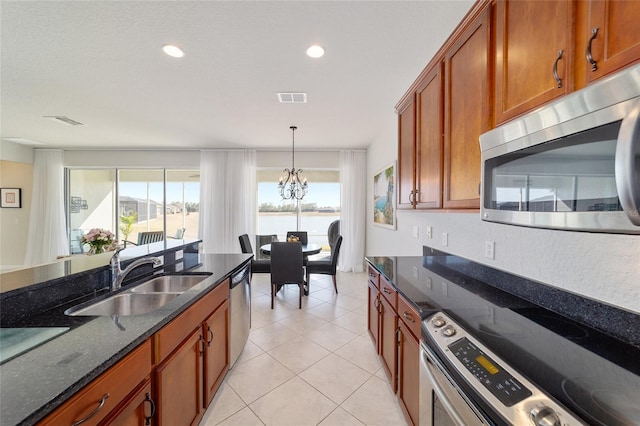 kitchen with appliances with stainless steel finishes, sink, a chandelier, dark stone counters, and light tile patterned floors