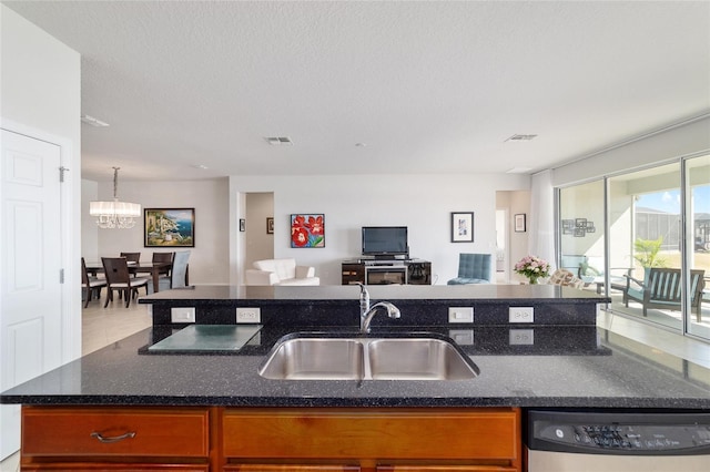 kitchen with dishwasher, sink, a center island with sink, and a textured ceiling