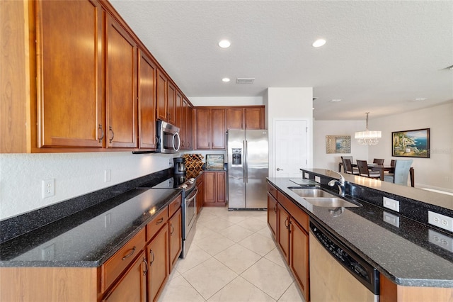 kitchen with appliances with stainless steel finishes, sink, dark stone countertops, and pendant lighting