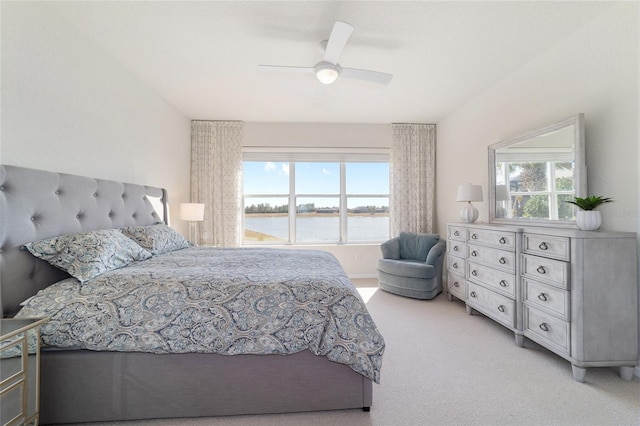 bedroom featuring a water view, light colored carpet, and ceiling fan