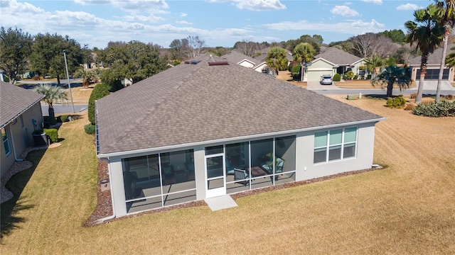 back of house with a sunroom and a lawn