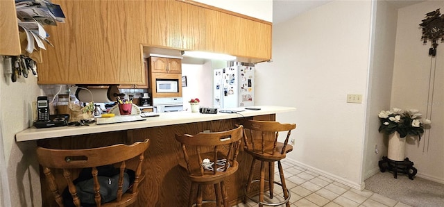 7651 SE 36th Ave, Ocala, FL 34480 - kitchen featuring light countertops, a peninsula, white appliances, baseboards, and a breakfast bar area