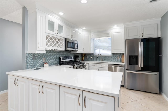 kitchen featuring sink, stainless steel appliances, white cabinets, light tile patterned flooring, and kitchen peninsula