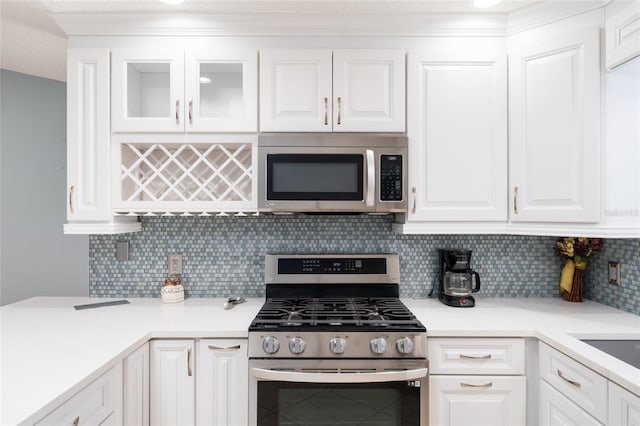 kitchen with appliances with stainless steel finishes, white cabinets, and decorative backsplash