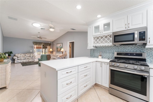 kitchen featuring lofted ceiling, tasteful backsplash, kitchen peninsula, stainless steel appliances, and white cabinets