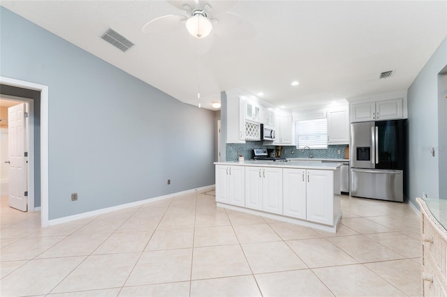 kitchen featuring white cabinetry, light tile patterned floors, appliances with stainless steel finishes, ceiling fan, and backsplash