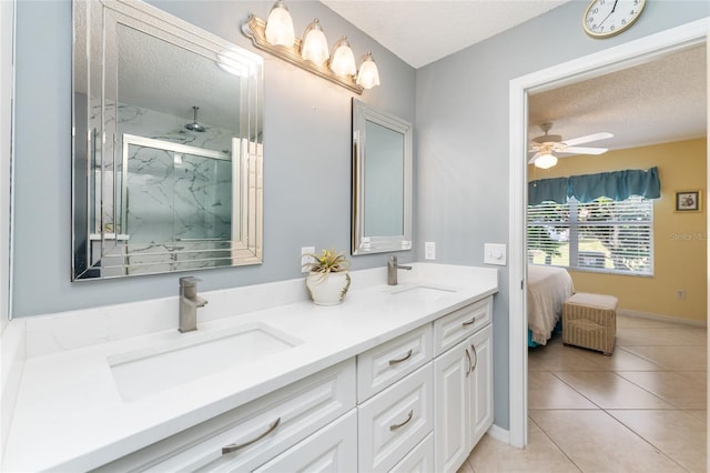 bathroom with tile patterned flooring, vanity, ceiling fan, a shower with door, and a textured ceiling