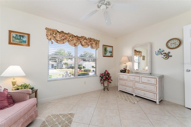 living area featuring ceiling fan, light tile patterned floors, and a textured ceiling