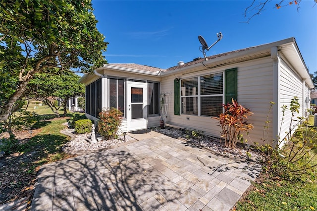 rear view of house featuring a sunroom and a patio