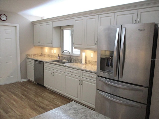 kitchen featuring wood finished floors, appliances with stainless steel finishes, a sink, and white cabinetry