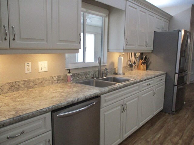 kitchen with stainless steel appliances, a sink, light countertops, and white cabinetry