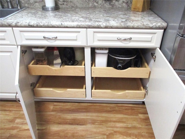 room details with wood finished floors, a sink, and white cabinets