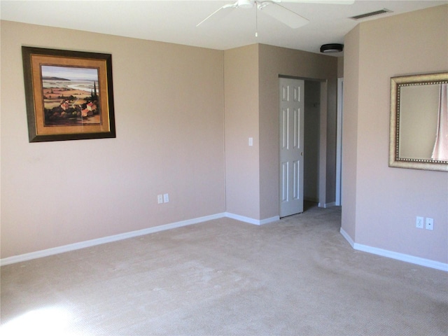 empty room with light carpet, baseboards, visible vents, and a ceiling fan