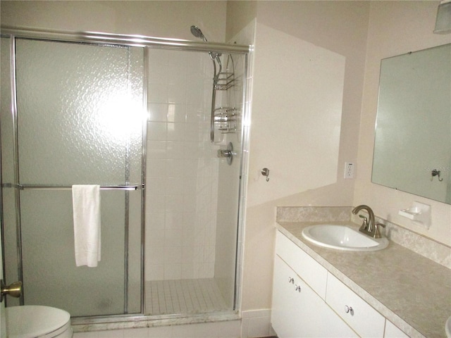 bathroom with a stall shower, vanity, and toilet