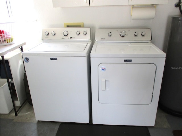 clothes washing area with laundry area, water heater, and washer and dryer