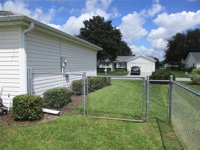 view of yard featuring a garage, a gate, and fence