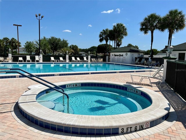 community pool featuring a community hot tub, a patio area, and fence