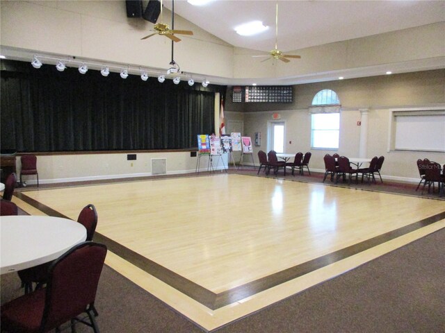 interior space with ceiling fan, high vaulted ceiling, wood finished floors, and baseboards