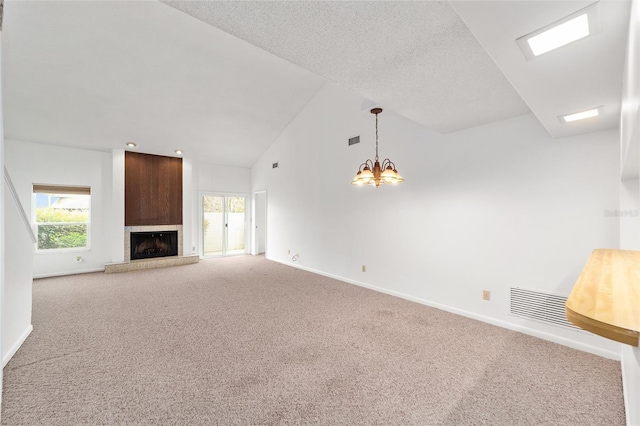 unfurnished living room with a notable chandelier, a fireplace, a textured ceiling, and carpet