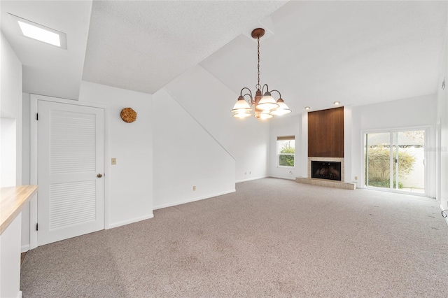 unfurnished living room with an inviting chandelier, a fireplace, vaulted ceiling, and carpet