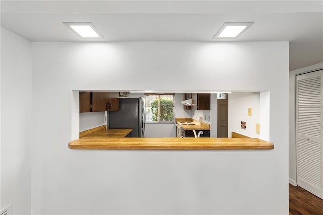 kitchen featuring stainless steel refrigerator, range hood, dark wood-type flooring, white range with electric cooktop, and dark brown cabinets