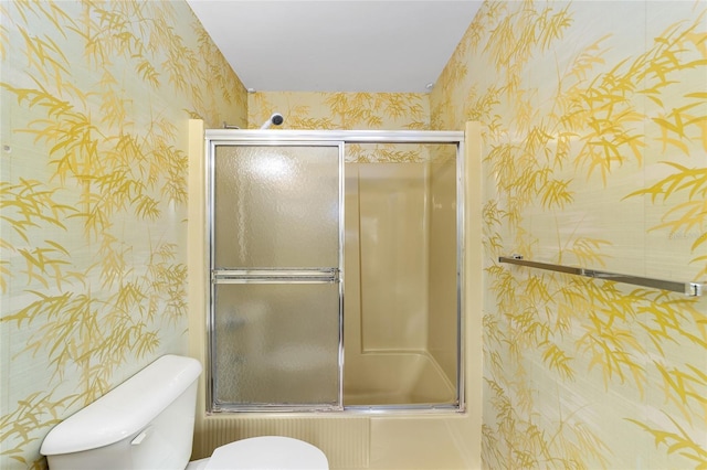 bathroom featuring enclosed tub / shower combo and toilet