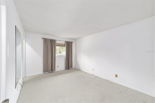 empty room with light colored carpet and a textured ceiling