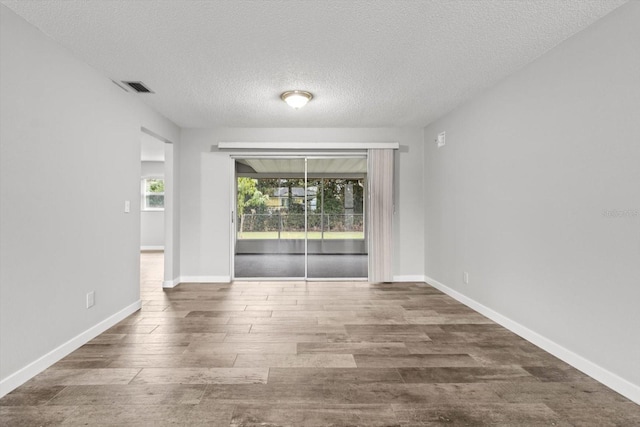 unfurnished room with dark wood-type flooring and a textured ceiling