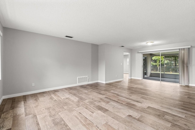 unfurnished room featuring a textured ceiling and light wood-type flooring