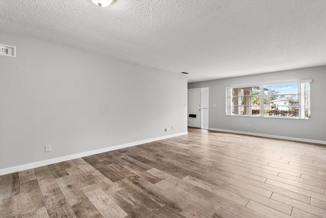 empty room featuring a textured ceiling and light hardwood / wood-style floors