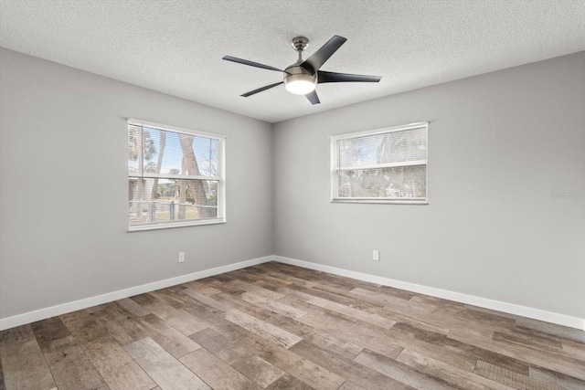 empty room with ceiling fan, light hardwood / wood-style flooring, and a textured ceiling