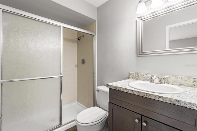 bathroom with a shower with door, vanity, and toilet