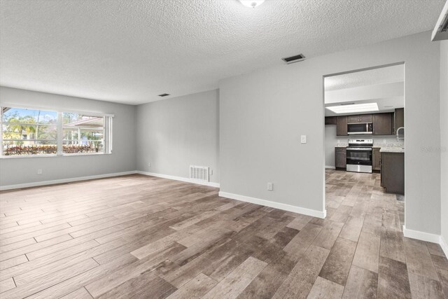 empty room featuring a textured ceiling and light wood-type flooring