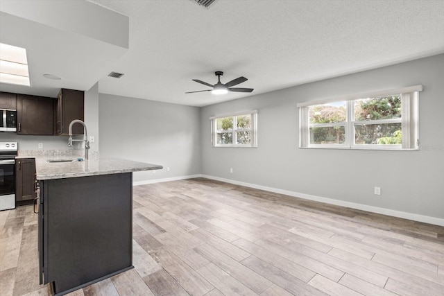 kitchen featuring a healthy amount of sunlight, light stone counters, dark brown cabinetry, and electric stove