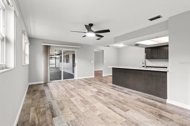 unfurnished living room featuring ceiling fan, light hardwood / wood-style floors, and a textured ceiling