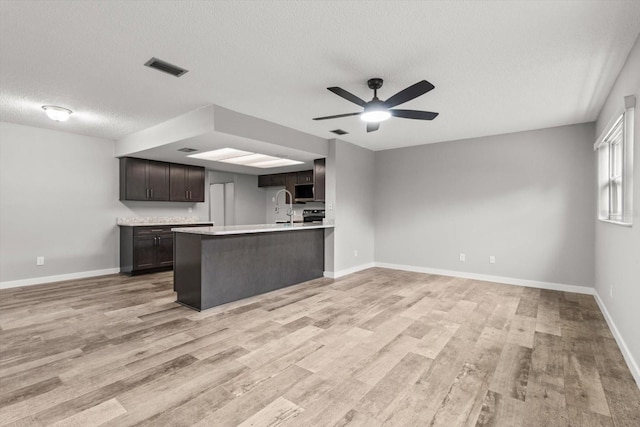 kitchen featuring light hardwood / wood-style flooring, ceiling fan, dark brown cabinets, and a textured ceiling