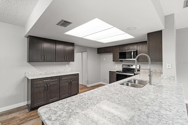 kitchen featuring dark brown cabinets, appliances with stainless steel finishes, sink, and wood-type flooring