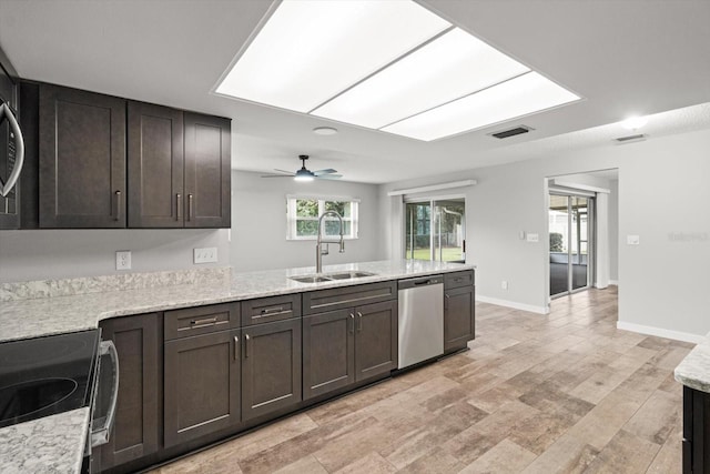 kitchen featuring dark brown cabinetry, appliances with stainless steel finishes, a skylight, and sink