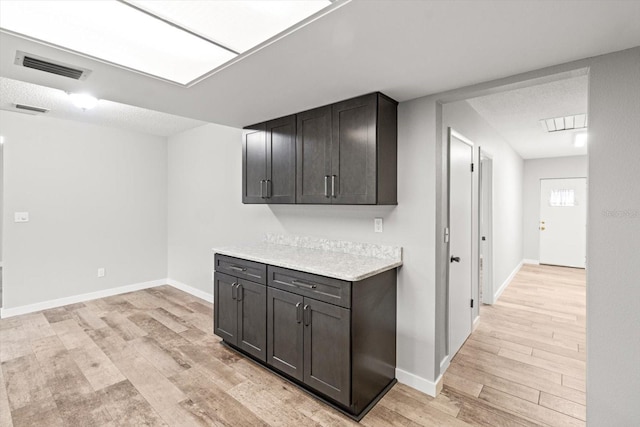 kitchen with dark brown cabinetry, light hardwood / wood-style flooring, and a textured ceiling