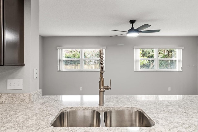 kitchen with light stone countertops, sink, a wealth of natural light, and a textured ceiling