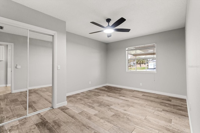 unfurnished bedroom featuring light hardwood / wood-style floors, a textured ceiling, ceiling fan, and a closet